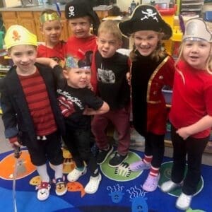 A group of kids in pirate costumes posing together in a classroom photo.