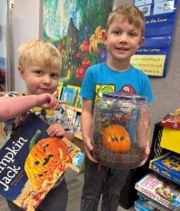 ps 1028 2 - First Lutheran Church and School, Helena, MT Two young boys in a store display: one holds a Pumpkin Jack book, the other shows a small carved pumpkin inside a clear plastic container.
